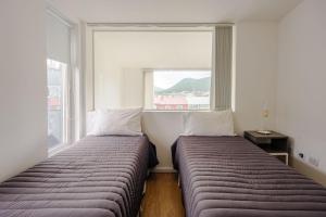 two beds in a room with a window at Gray Fox Apartments - Deloqui in Ushuaia