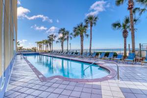 a swimming pool with palm trees and the ocean at Sterling Reef 907 - Brent's Beach in Panama City Beach