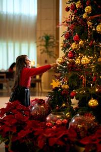 a woman is decorating a christmas tree at Kempinski Nile Hotel, Cairo in Cairo