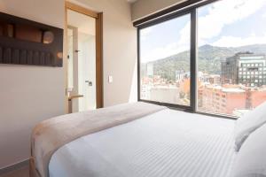 a bedroom with a white bed and a large window at Luxury ultramodern in club house building with poolspa in Bogotá