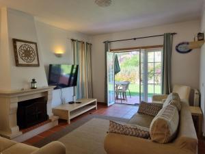 a living room with a couch and a tv at Praia D'El Rey - Townhouse Dom Duarte in Amoreira