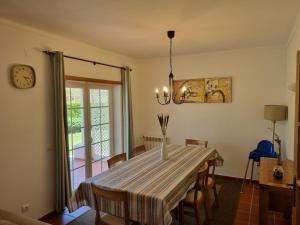 a dining room with a table with chairs and a clock at Praia D'El Rey - Townhouse Dom Duarte in Amoreira