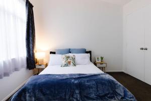 a bedroom with a bed with a blue blanket on it at Spacious 3BR Retreat on City Fringe w Free Parking in Wellington