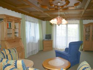 a living room with a blue couch and a tv at Gästehaus Steiger in Bad Birnbach