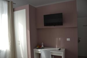 Zimmer mit einem TV an der Wand und einem Tisch in der Unterkunft In Centro Glam in Bergamo