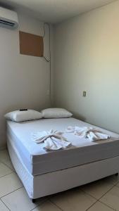 a bed with white sheets and pillows on it at Condomínio Jardim Presidente 08 in Cuiabá