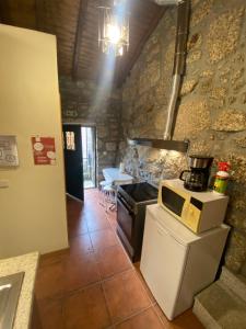 eine Küche mit Herd und Mikrowelle in der Unterkunft Refúgio Rural no Gerês - Casa Araujo de Sousa in Terras de Bouro