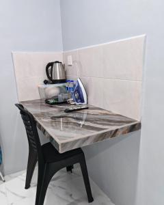 a kitchen counter with a table and a chair at Cms Roomstay Alor Setar in Alor Setar