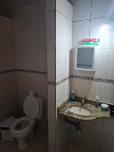a bathroom with a toilet and a tv on the wall at Casa espaçosa bem localizada in Belém