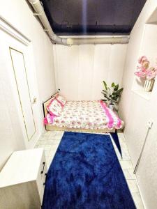 a small room with a bed and a blue carpet at Easy Comfort Hostel in Tashkent