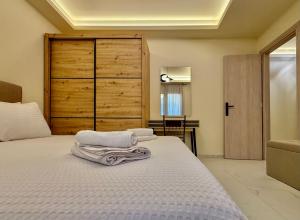 a bedroom with a white bed with a wooden door at GK Luxury Suites in Alexandroupoli +26 photos