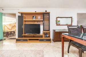 a living room with a tv and a entertainment center at Piratas de Geriba Guest Rooms in Búzios