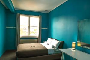 a blue bedroom with a bed and a window at Crashpalace Backpackers in Rotorua