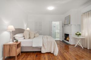 une chambre blanche avec un lit et une cheminée dans l'établissement Lavender Cottage Alpine Southern Highlands, à Alpine