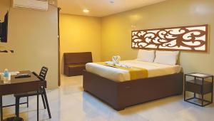 a bedroom with a bed with a desk and a chair at Algers Suites in Manila