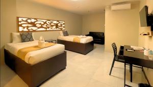 a hotel room with two beds and a desk at Algers Suites in Manila