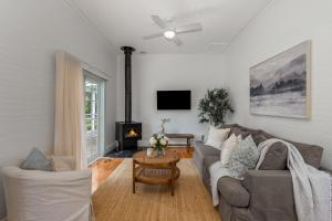 un salon avec un canapé et une cheminée dans l'établissement Oatley Cottage Alpine Southern Highlands, à Alpine
