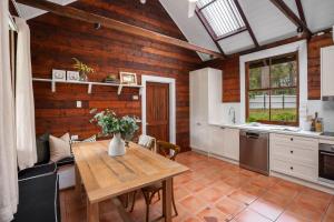 a kitchen with a table and a wooden wall at Pottery Cottage, Alpine, Southern Highlands in Alpine