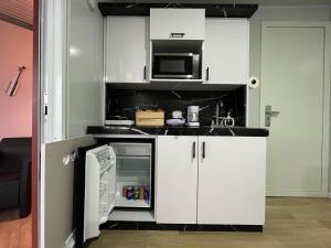 a small kitchen with white cabinets and a microwave at Mirada al Mar 01 in Camaceyes