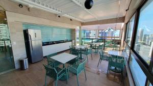 ein Restaurant mit Tischen und Stühlen sowie einem Kühlschrank in der Unterkunft Rooftop 470 #Flat 1005 - Boa Viagem in Recife