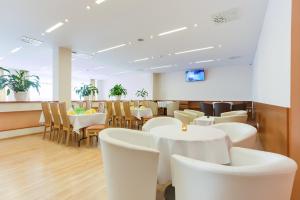 uma sala de jantar com mesas e cadeiras brancas em Hotel Lineas em Presov