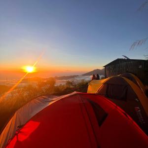 a group of tents on a hill with the sunset at LuxeTent Batur Peak in Kintamani