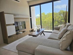 a living room with a couch and a large window at Mangle 13 Modern Apartments-Rooftop pool, close to Ferry in Cancún