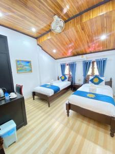 a bedroom with two beds and a flat screen tv at Singharat Boutique House in Luang Prabang