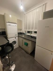 a kitchen with a white refrigerator and a dishwasher at Brixton Attic in London