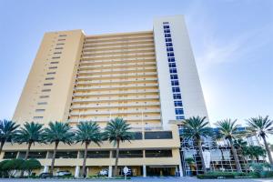 a large building with palm trees in front of it at Sterling Reef 907 - Brent's Beach in Panama City Beach