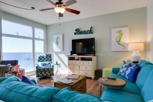 a living room with a blue couch and a tv at Sterling Reef 907 - Brent's Beach in Panama City Beach