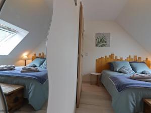 two beds in a attic room with a mirror at Maison ancienne avec sauna, babyfoot, billard, proche station thermale et forêt domaniale - FR-1-497-136 in La Chapelle d'Audaine