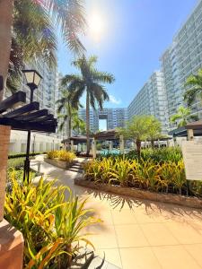 a walkway with palm trees and plants and buildings at Shell Residences Condotel by PauL in Manila