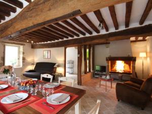 Una sala de estar con una mesa y una chimenea. en Grange restaurée avec jardin, charme et confort près d'Alençon - FR-1-497-24, en Alençon