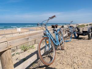due biciclette parcheggiate accanto a una recinzione in spiaggia di Maison de 40m² à Biscarrosse - Proche lac, pistes cyclables, plage - Accueille 4 pers. - Animaux OK - FR-1-319-484 a Biscarrosse