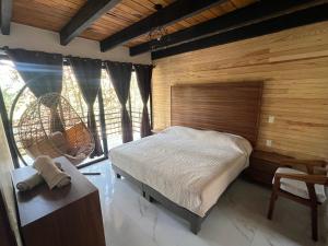 a bedroom with a bed and a large window at Hermosa cabaña en el bosque in Mazamitla