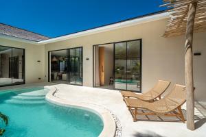 ein Swimmingpool mit zwei Stühlen und einem Haus in der Unterkunft Dreamy 2BR pool villa, steps from Gili Air beach in Gili Air