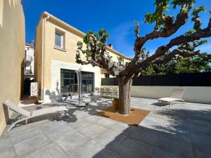 a patio with a tree and chairs next to a building at Charmante maison familiale pour 10 personnes, spacieuse et confortable - FR-1-309-511 in Banyuls-sur-Mer