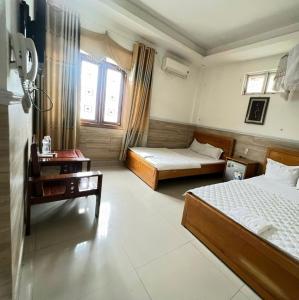 a hotel room with two beds and a desk and window at Khách sạn Limousine in Kon Tum