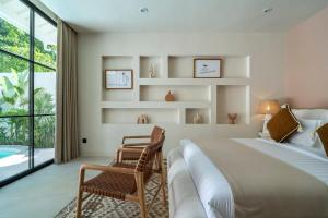 ein Schlafzimmer mit einem Bett und einem Stuhl und einem Fenster in der Unterkunft Dreamy 2BR pool villa, steps from Gili Air beach in Gili Air + 33 Fotos