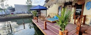 a house with a wooden deck with an umbrella and water at Al Mare Karimunjawa in Karimunjawa