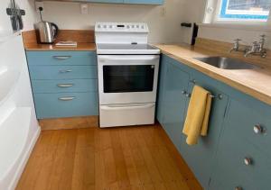 Il comprend une cuisine équipée d'une cuisinière, d'un évier et de placards bleus. dans l'établissement Paekākāriki Cottage near the Sea, à Paekakariki