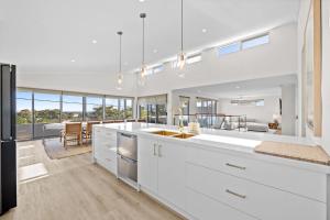a kitchen with white cabinets and a dining room at Silver Sands Sanctuary - 6BR Beachside Luxury in Mandurah