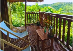 a wooden deck with two chairs and a table on it at Busuanga Nature Retreat in Busuanga