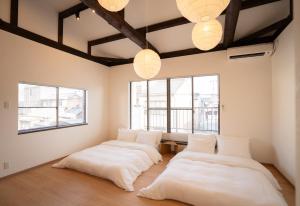 two beds in a room with windows and lights at OneStay一宿 無料駐車場 駅徒歩2分 和モダン一軒家 小庭付き 静か お子様連れに優しい 名古屋駅近 in Nagoya +77 photos