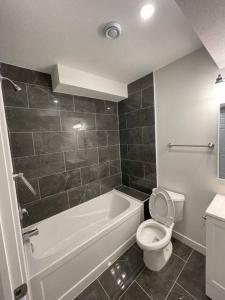 y baño con bañera blanca, aseo y lavamanos. en Bedroom in Southwest C, en Edmonton