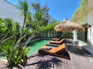 a pool with two lounge chairs and a straw umbrella at Villa Mei, 2BR Pool, Seseh Beach in Dalung