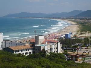 Blick auf einen Strand mit Gebäuden und das Meer in der Unterkunft Joaquina Beach Hotel in Florianópolis