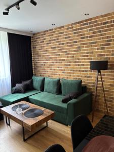 a living room with a green couch and a brick wall at Biała Centrum 2 in Biała Podlaska