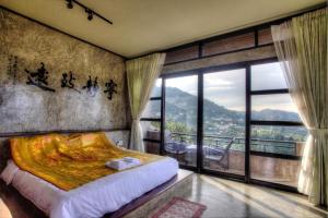 a bedroom with a bed and a large window at Baan Hom Muen Li in Mae Salong